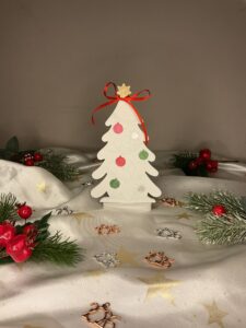 Λευκό πορσελάνινο χριστουγεννιάτικο δέντρο με ζωγραφισμένα στολίδια, κόκκινη κορδέλα και χρυσό αστέρι στην κορυφή.