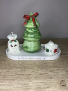 Χριστουγεννιάτικη χειροποίητη σύνθεση με τρία κεριά πάνω σε λευκή βάση, με πράσινο κερί-δεντράκι στο κέντρο και διακοσμητικά λευκά κεριά δεξιά και αριστερά